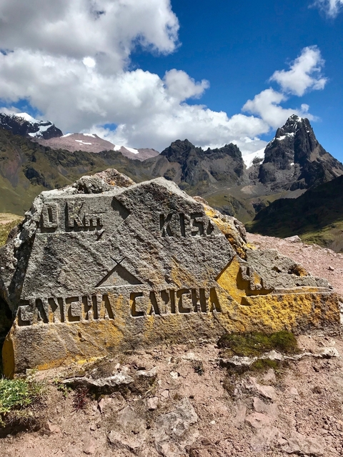       Rock marker with distance and trail information, surrounded by mountains.
  
