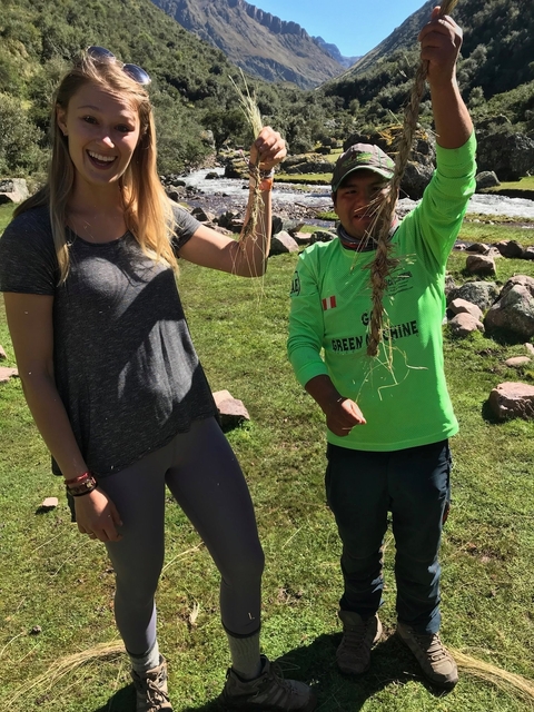       Two people holding plants outside.
  