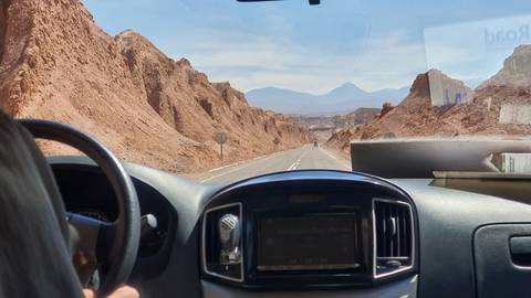       Desert landscape viewed from inside a vehicle.
  