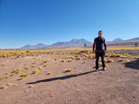 Person standing in a vast desert landscape with mountains.
