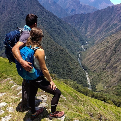       Couple overlooking a vast valley with a river below.
  