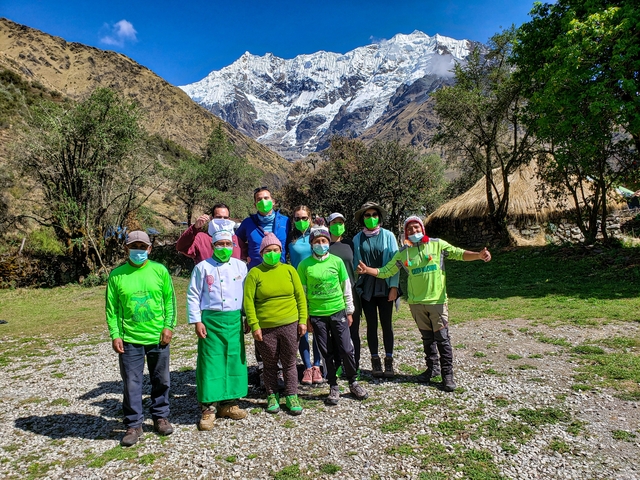       Group posing with masks in front of snow-capped mountains.
  