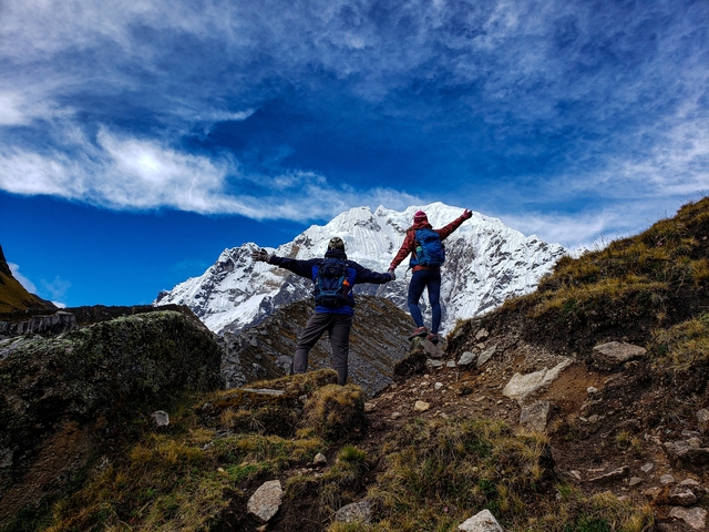      Hiking couple with arms outstretched against a snow-capped mountain.
  