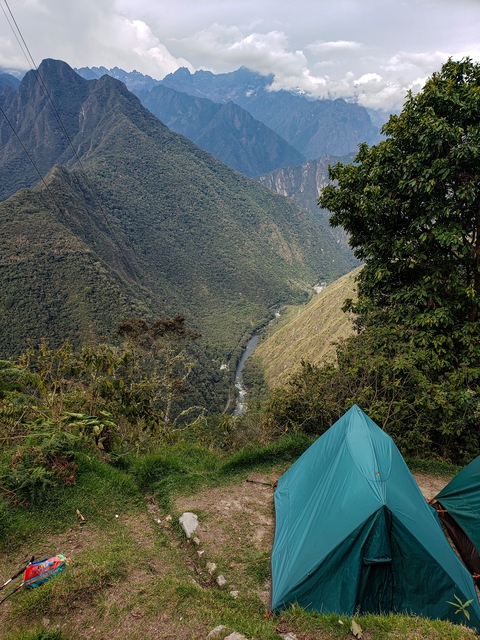       View of a tent overlooking a deep valley with river.
  
