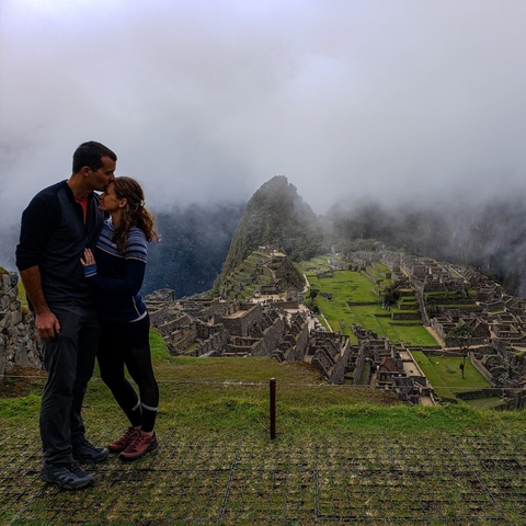       Couple kissing with Machu Picchu ruins in the background.
  