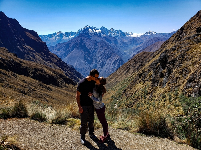       Couple kissing with scenic mountain backdrop.
  
