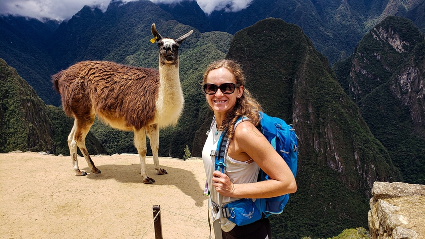       Woman with a llama at a mountain viewing point.
  