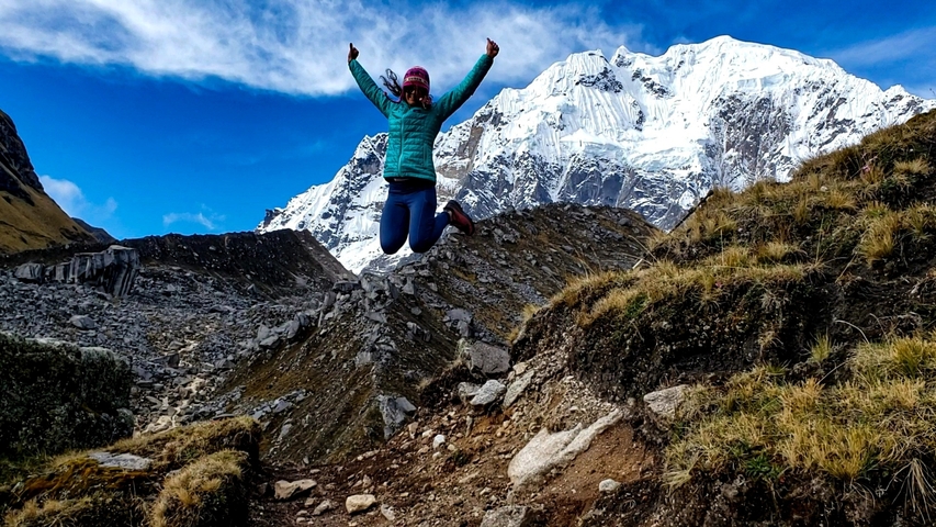       Person jumping in excitement with snowy mountain backdrop.
  