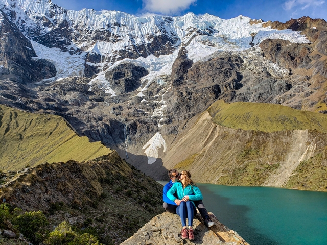       Couple sitting with a view of a lagoon and mountains.
  