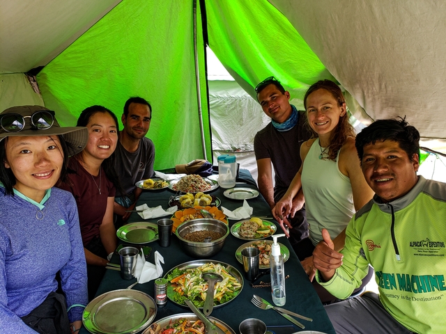       Group seated inside a tent dining with a view outside.
  
