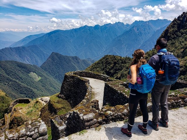       Couple admiring a vast mountain landscape.
  