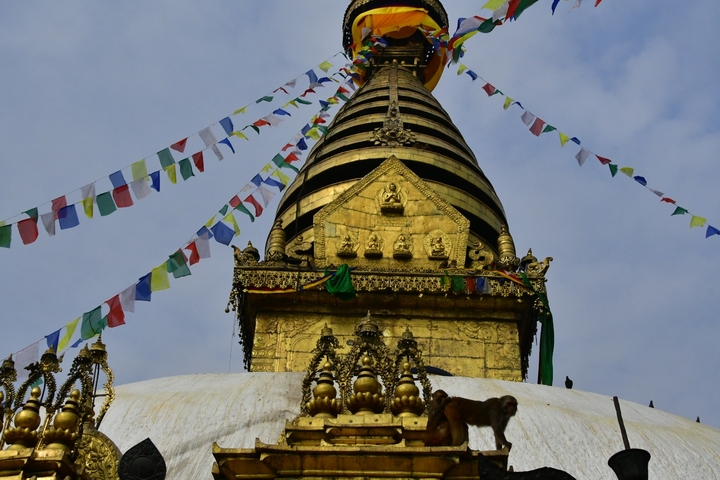       The stupa with prayer flags fluttering against a clear sky.
  