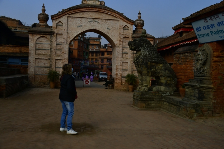 Person looking at a traditional archway and statue.