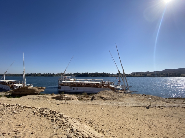       Boats moored along a riverbank against a clear sky.
  