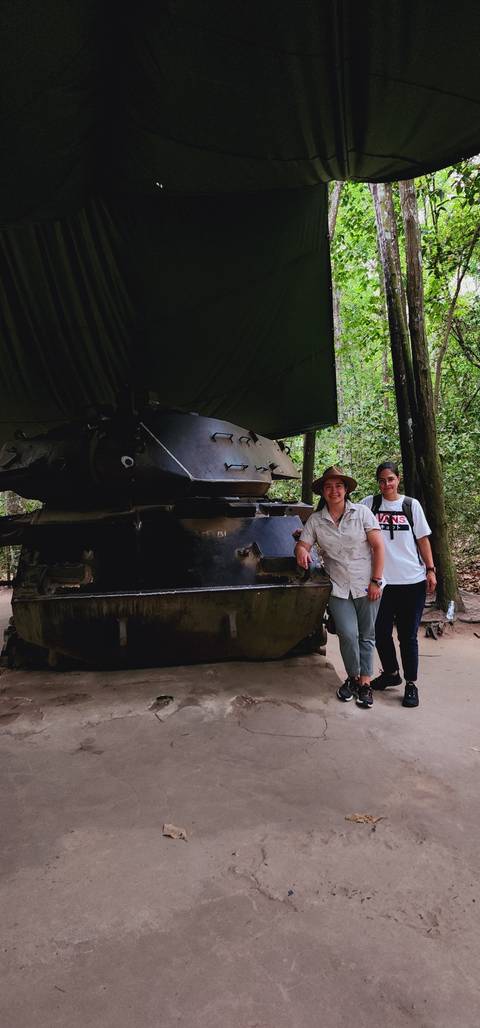 Two people standing by an old military tank.