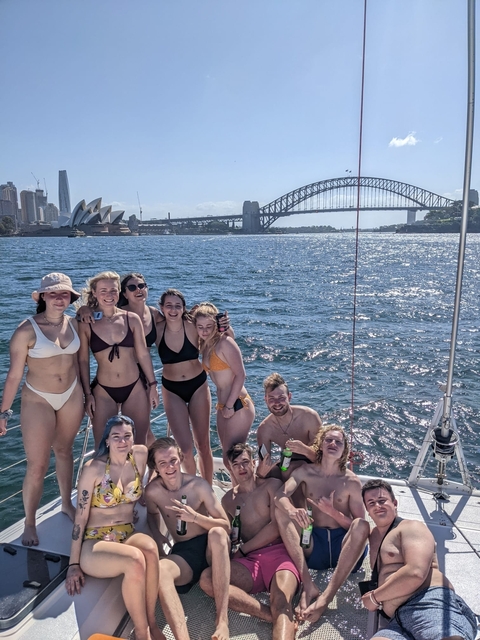 Group of people on a boat with Sydney Opera House and Harbour Bridge in the background.