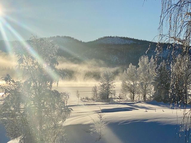 Sunlit snowy landscape with mist over vast landscapes.
