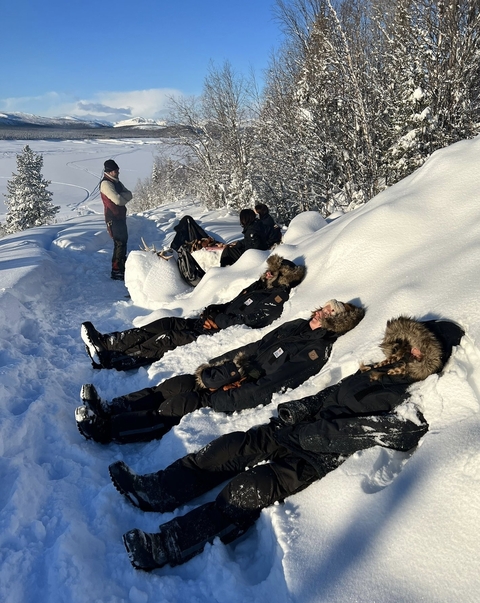 People in winter clothing lying in the snow, enjoying the sun.