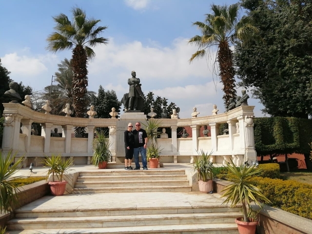       Two people standing in front of a statue with surrounding sculptures.
  