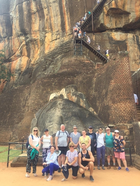       Group of people in front of a large rock fortress.
  