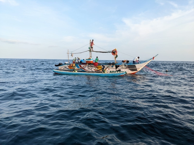       Fishing boat with fishermen on the sea.
  