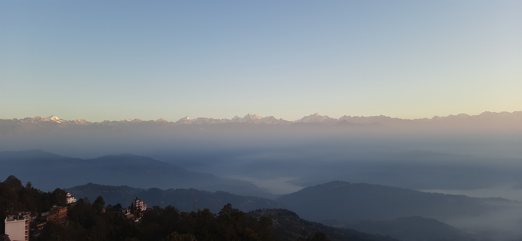 Mountain view with mist and forested hills.