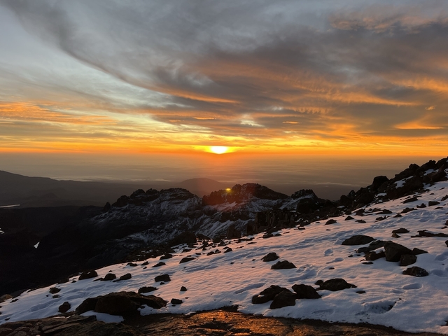       A stunning sunset over a snowy mountainous landscape.
  