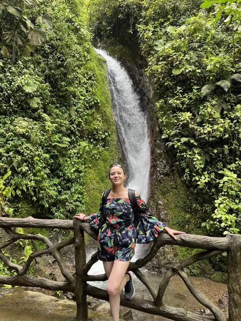 Person on a bridge with a small waterfall in the background.