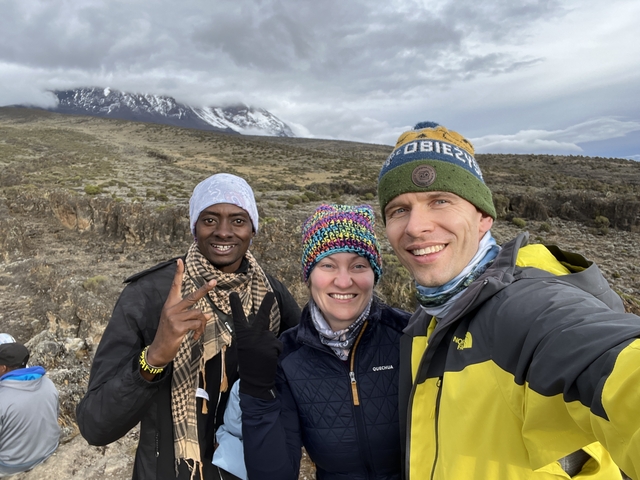 Three people posing with mountain background.