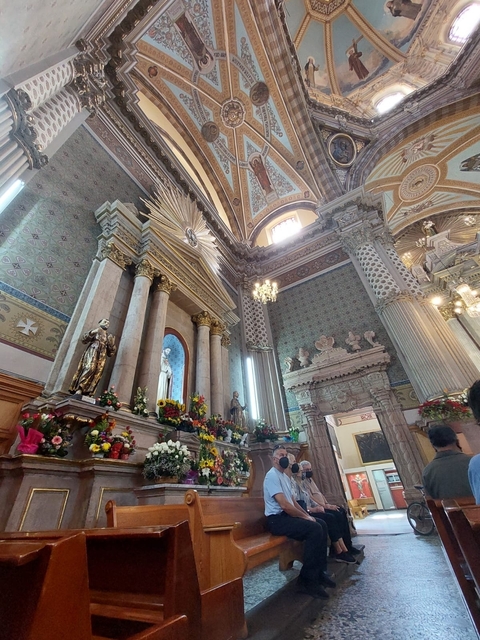       Interior of a grand church with ornate decor and flowers.
  