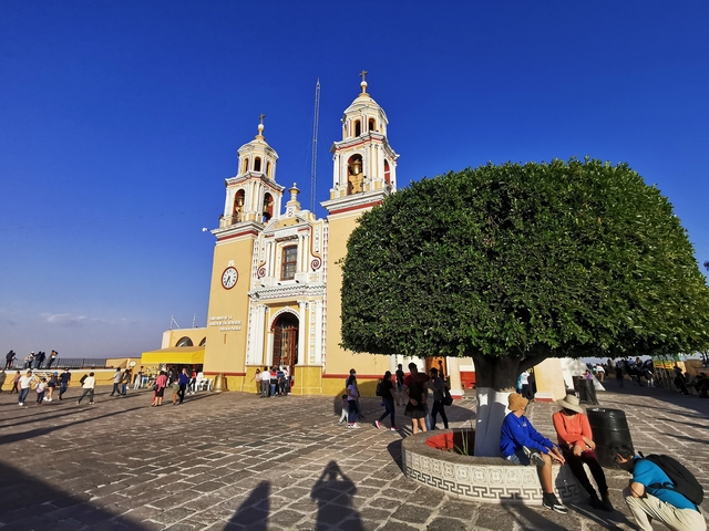       People outside a historic church with towers.
  