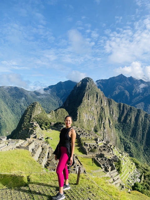 Person standing in front of Machu Picchu ruins with mountains in the background.