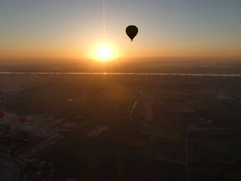 Hot air balloon silhouetted against the sunrise.