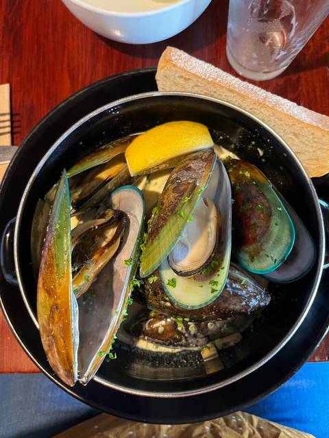 A dish of steamed mussels with a lemon wedge and broth.