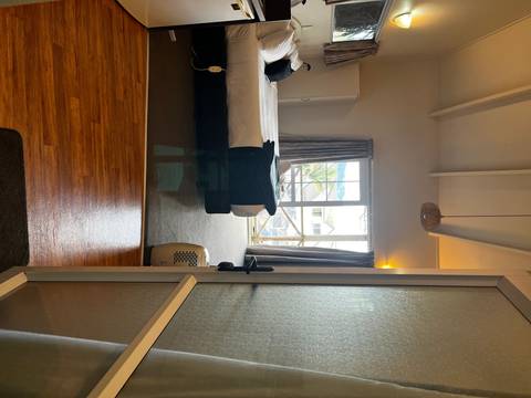 An indoor room with a bed facing a window overlooking a cityscape.