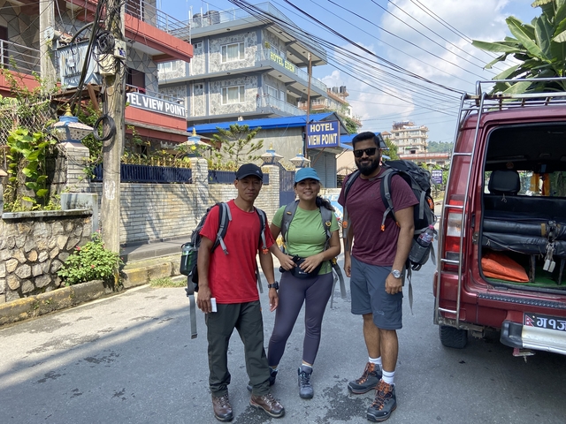       Three people with backpacks standing on a street with buildings.
  