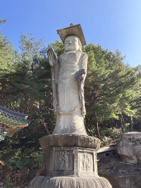       Statue of a standing figure amidst trees.
  
