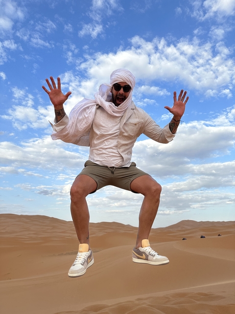 Man jumping in the air with a joyful expression in the desert.