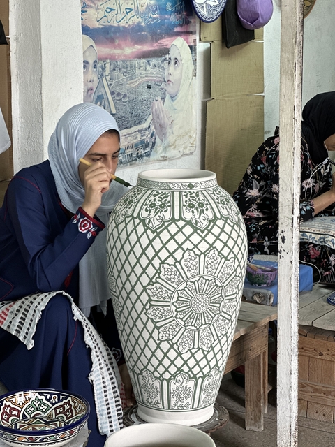 Woman hand-painting a traditional ceramic vase.