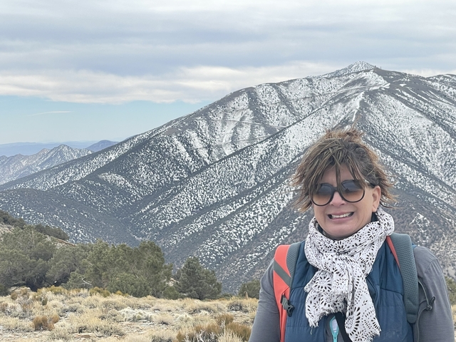       A person smiling with a snow-capped mountain in the background.
  