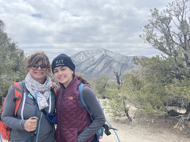 Two people smiling with a mountain in the background.