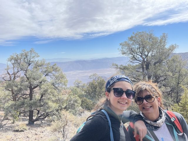 Two people taking a selfie with a mountainous landscape.