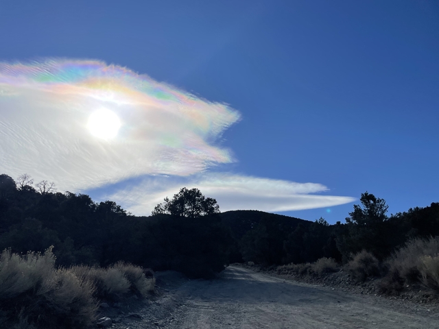 A scenic sky with a sun halo and silhouette of a mountain.
