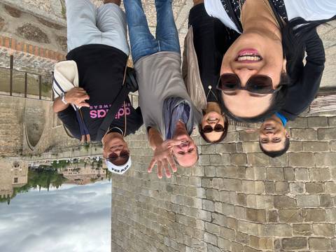       Group of people smiling with ancient stone walls in the background.
  