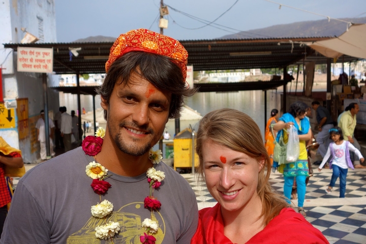 Two people wearing traditional garlands and tilak on their foreheads.