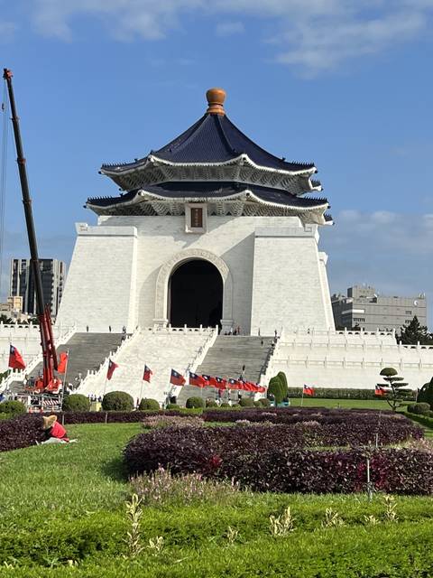 A large building with a traditional roof surrounded by a garden.