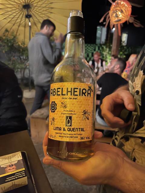       Person holding a bottle of liquor with people around.
  