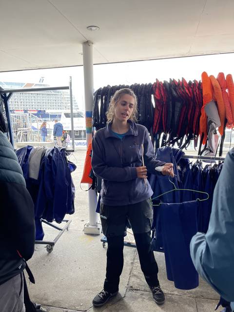 Person speaking in front of hanging clothes.