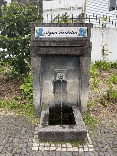       A stone fountain with the name 'Aqua Pedreira'.
  