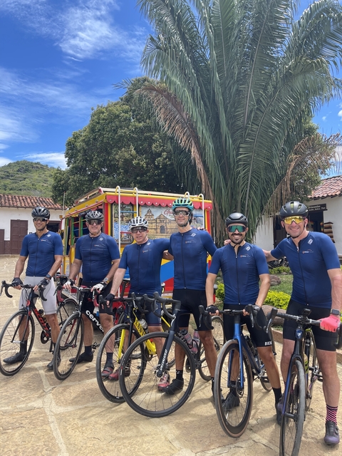 Group of cyclists posing with a colorful bus.